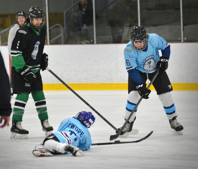 Austin Swope, center, hits the ice while York Polar Bears teammate Kai Gibson-Wright plays the puck during the third annual charity hockey game featuring the Polar Bears and the York College ice hockey team on Sunday, March 24, 2024 at the York Ice Arena.