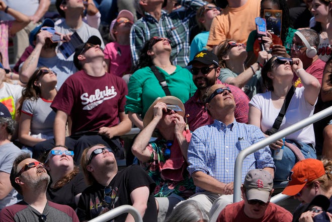 People watch with solar glasses as the moon starts to cross in front of the sun during a total solar eclipse Monday, April 8, 2024, in Carbondale, Ill. (AP Photo/Jeff Roberson)